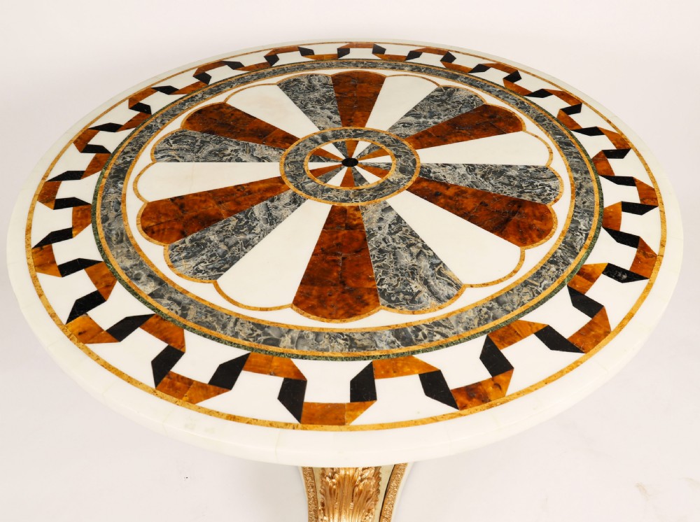 A circular centre table featuring an intricate geometric inlaid marble top supported by three carved gilt dolphin figures on a triform marble base. View IV