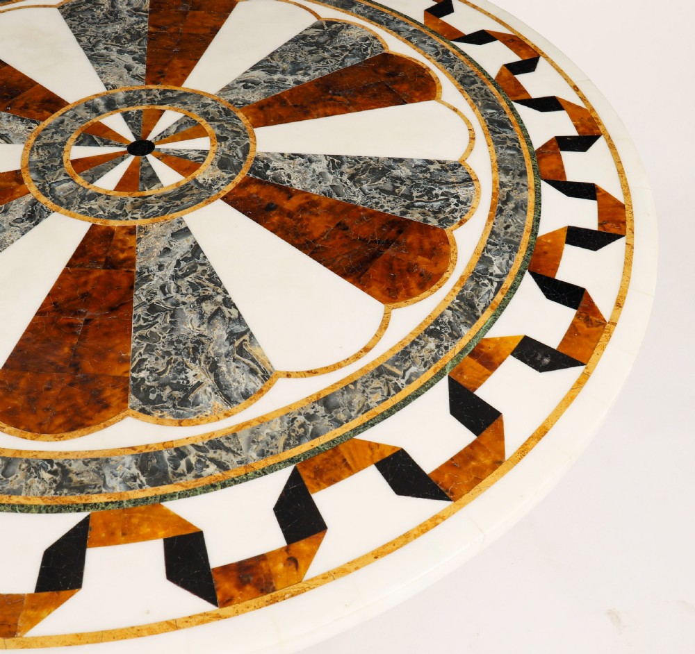 A circular centre table featuring an intricate geometric inlaid marble top supported by three carved gilt dolphin figures on a triform marble base. View VI