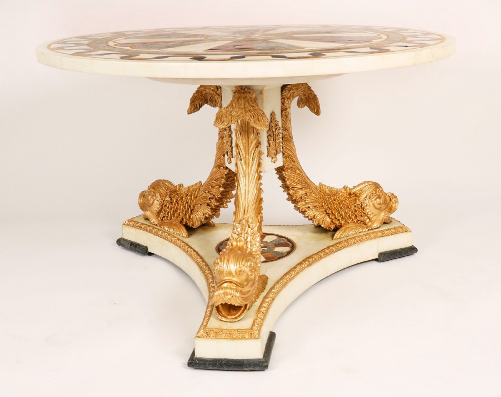 A circular centre table featuring an intricate geometric inlaid marble top supported by three carved gilt dolphin figures on a triform marble base. View VII