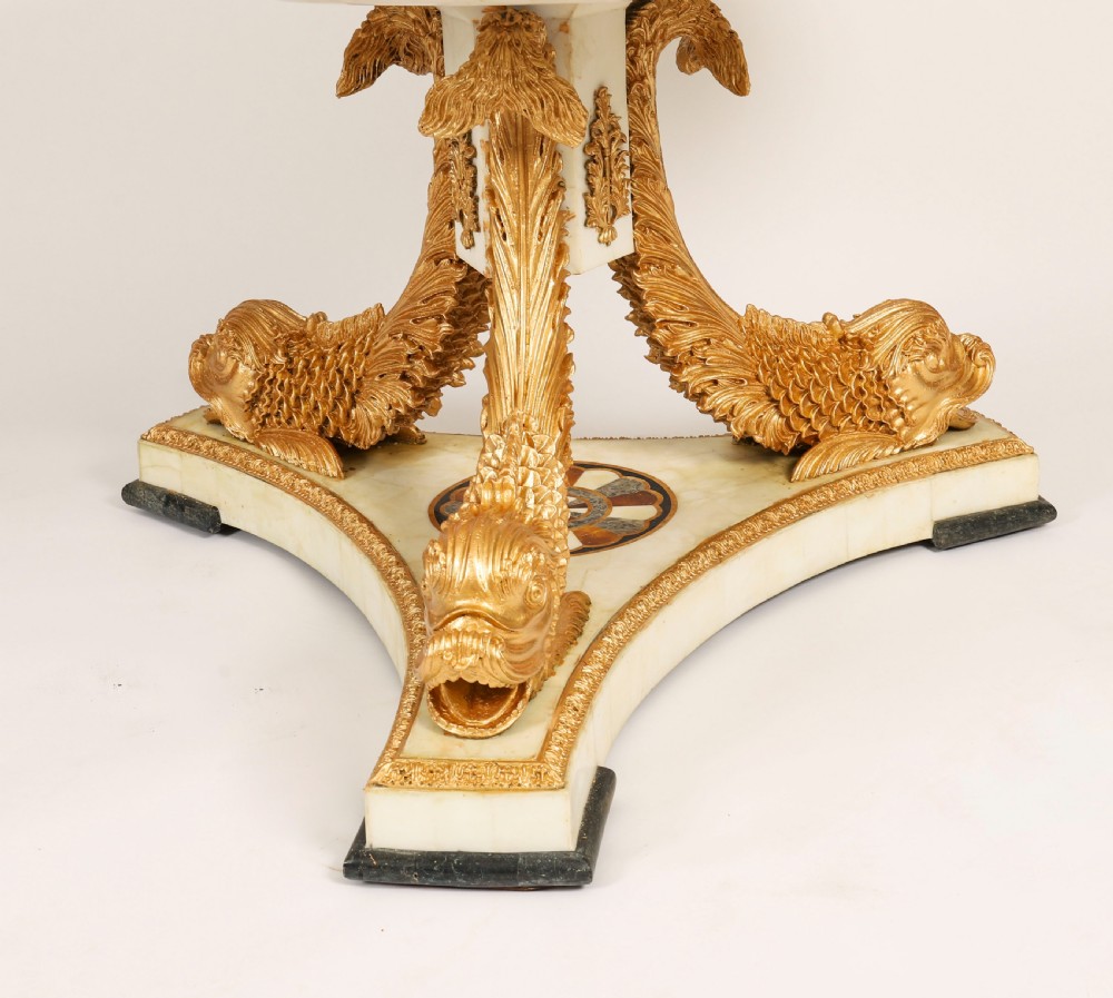 A circular centre table featuring an intricate geometric inlaid marble top supported by three carved gilt dolphin figures on a triform marble base. View VIII