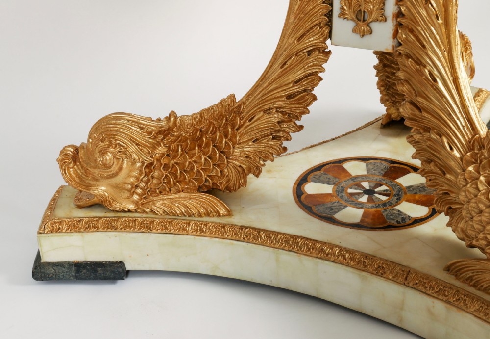 A circular centre table featuring an intricate geometric inlaid marble top supported by three carved gilt dolphin figures on a triform marble base. View XI