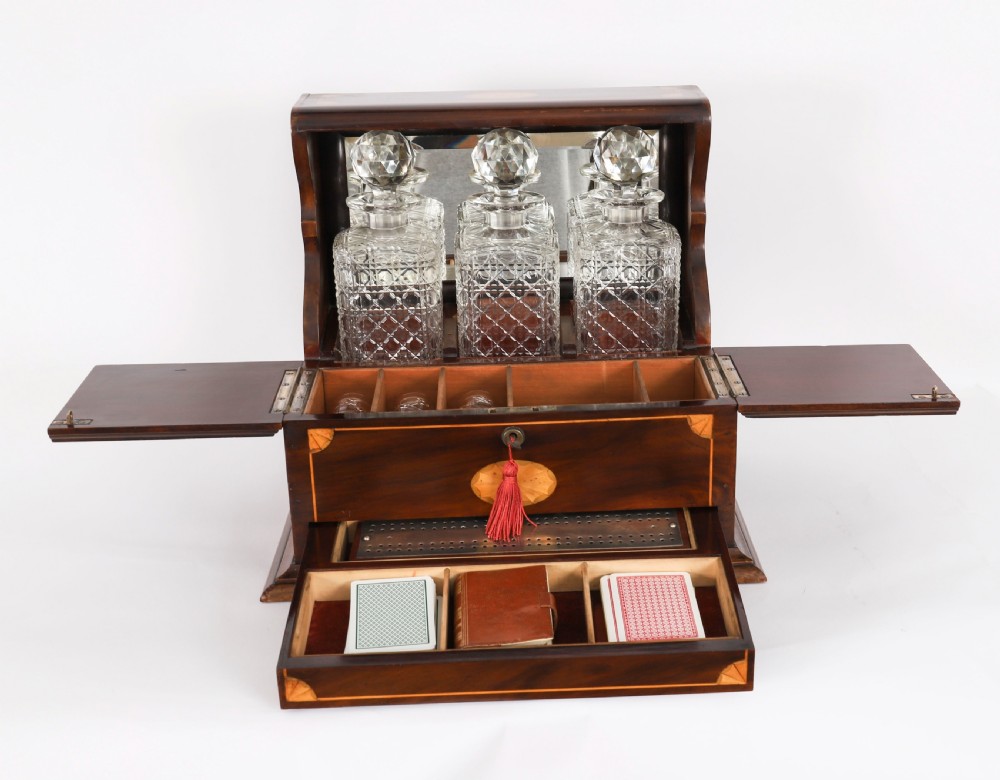 A 19th-century inlaid mahogany tantalus box containing three cut crystal decanters arranged in front of a mirrored back. View III