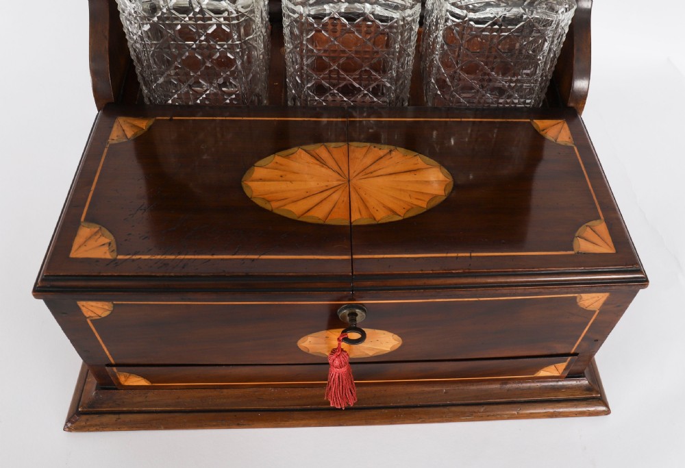 A 19th-century inlaid mahogany tantalus box containing three cut crystal decanters arranged in front of a mirrored back. View VII