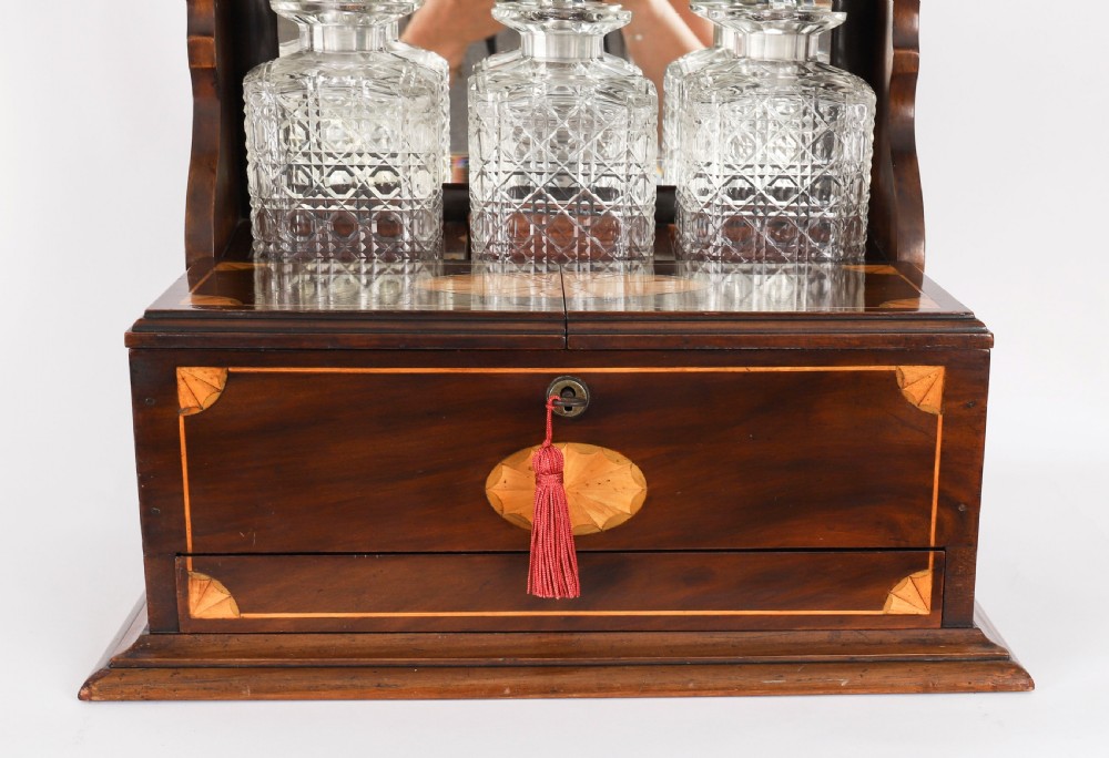 A 19th-century inlaid mahogany tantalus box containing three cut crystal decanters arranged in front of a mirrored back. View VIII