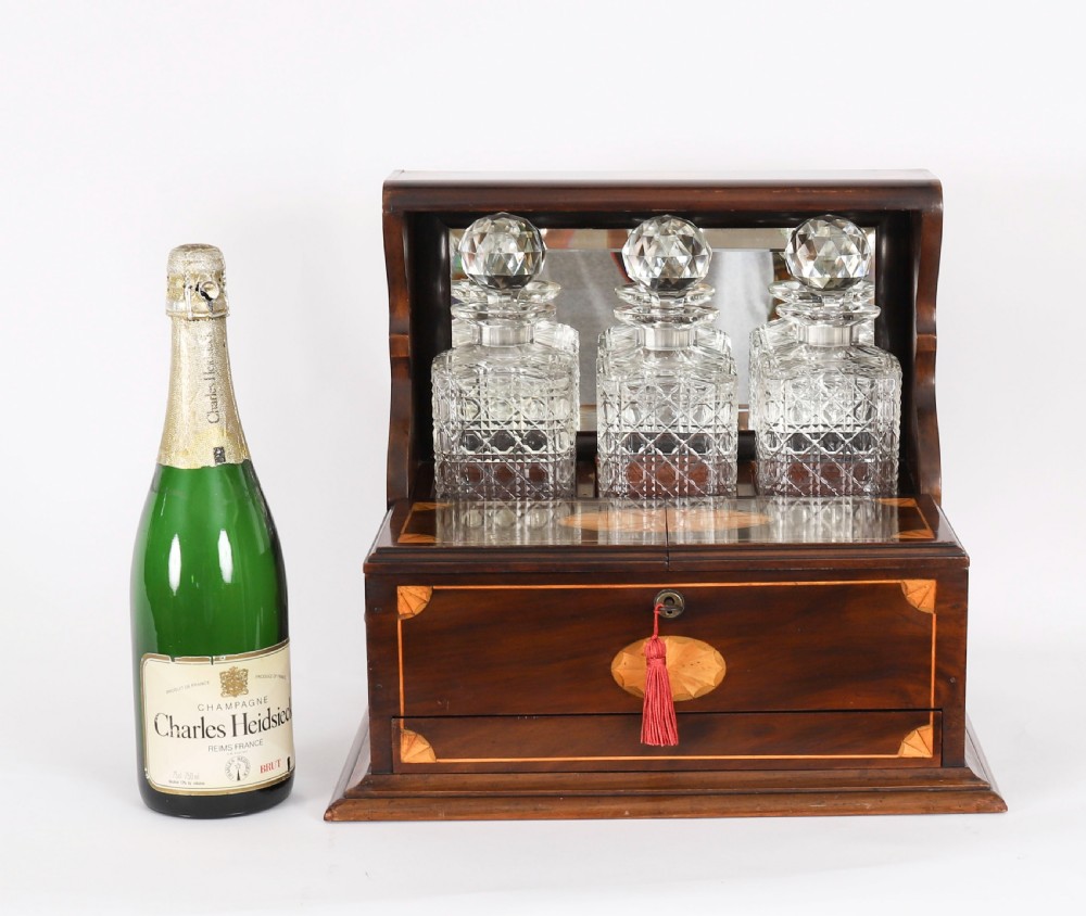 A 19th-century inlaid mahogany tantalus box containing three cut crystal decanters arranged in front of a mirrored back. View XIV