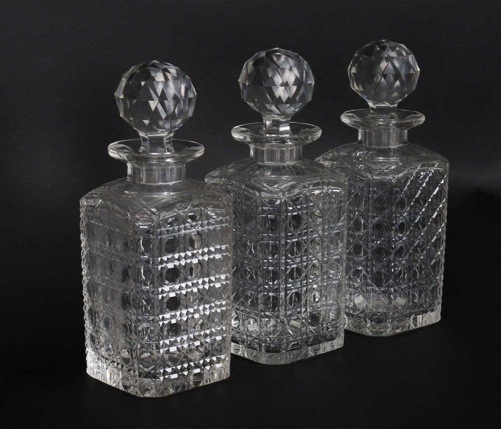A 19th-century inlaid mahogany tantalus box containing three cut crystal decanters arranged in front of a mirrored back. View XV
