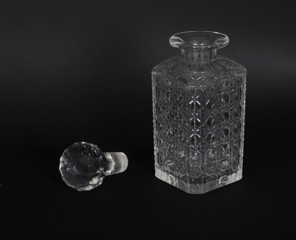 A 19th-century inlaid mahogany tantalus box containing three cut crystal decanters arranged in front of a mirrored back. View XVII