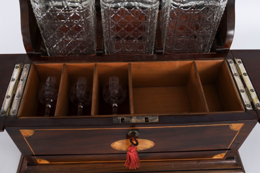 A 19th-century inlaid mahogany tantalus box containing three cut crystal decanters arranged in front of a mirrored back. View XIX