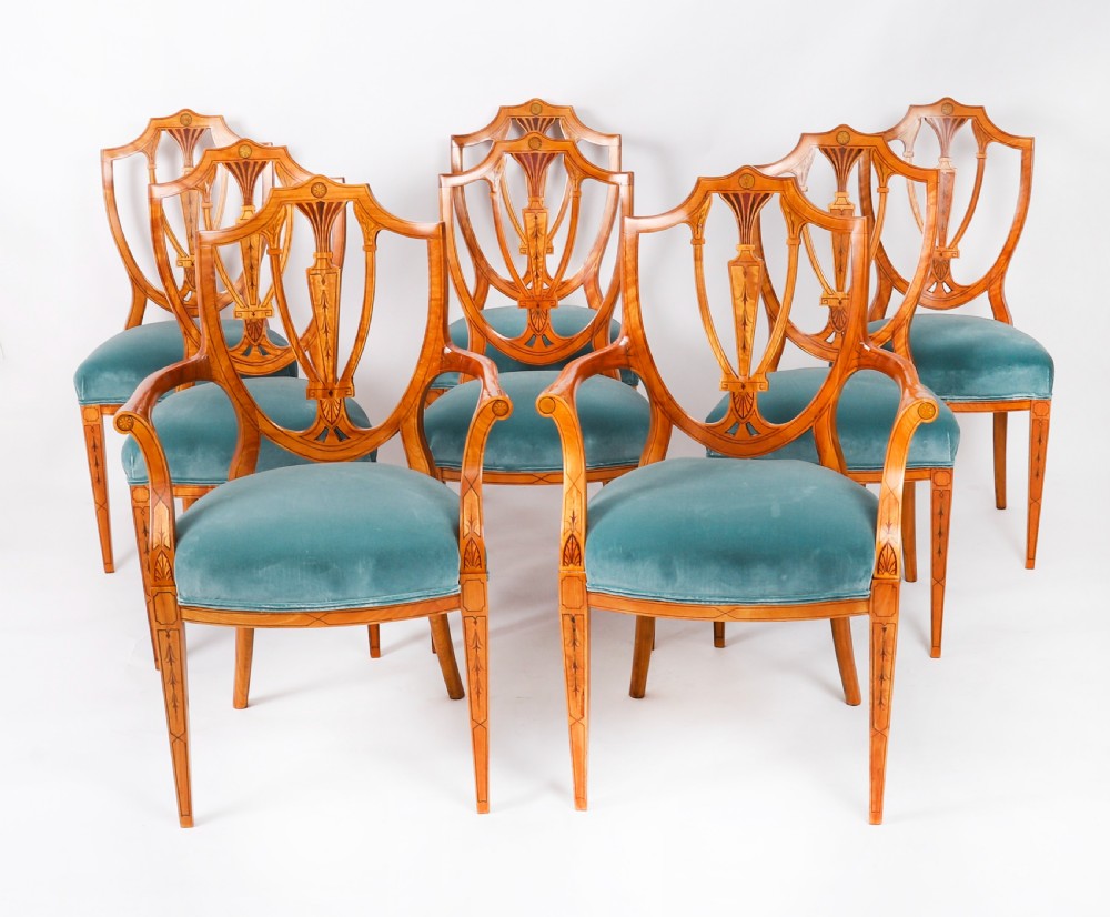 A set of eight antique satinwood shieldback dining chairs featuring classical marquetry inlay and teal velvet seats.