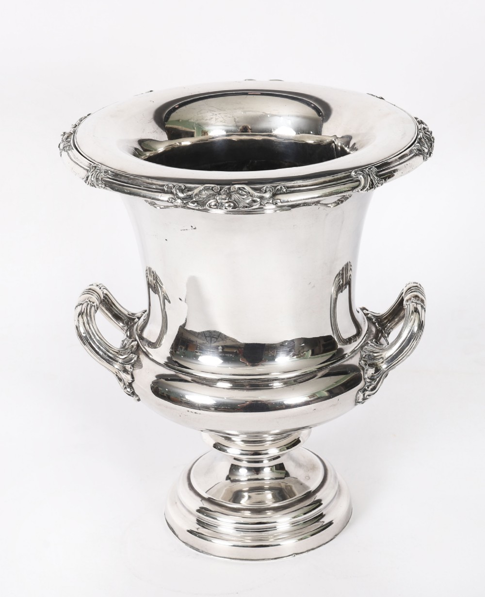 A pair of silver-plated urn-shaped wine coolers featuring scrolled side handles, engraved central crests, and circular pedestal bases. View IX