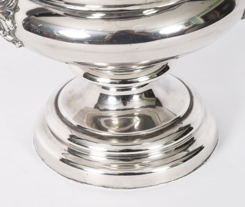 A pair of silver-plated urn-shaped wine coolers featuring scrolled side handles, engraved central crests, and circular pedestal bases. View XIX