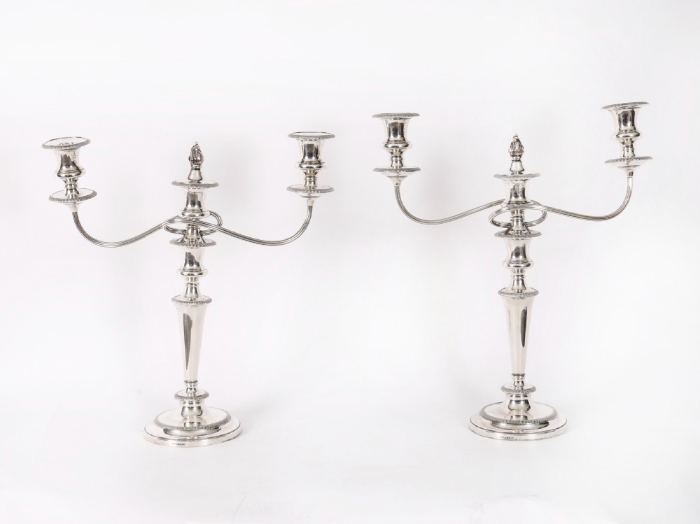 A pair of late nineteenth-century silver three-light candelabra featuring reeded curving arms, beaded circular bases, and central flame finials.
