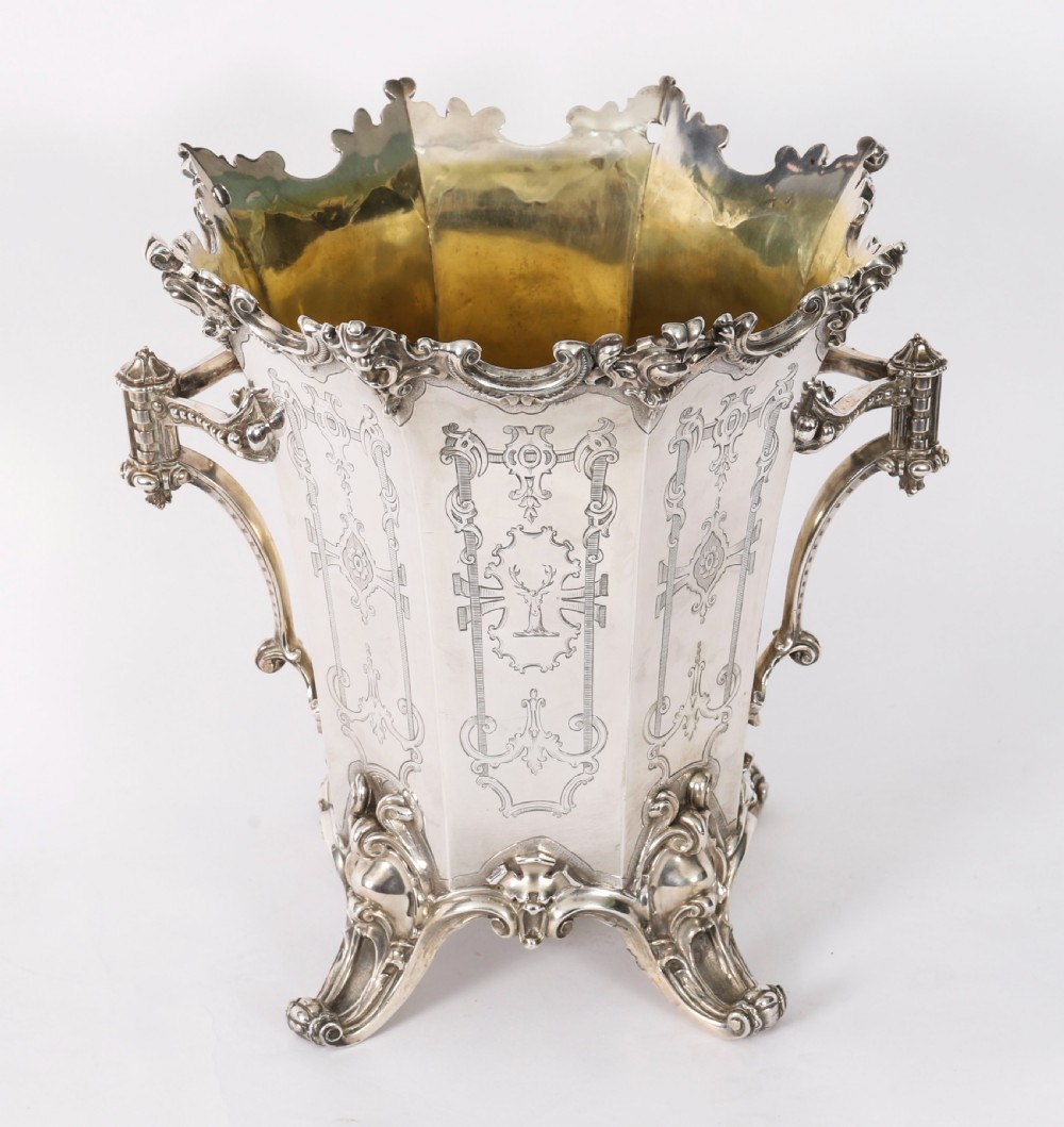A nineteenth-century silver-plated wine cooler featuring engraved panels, cast scroll feet, side handles, and a gilded interior wash.