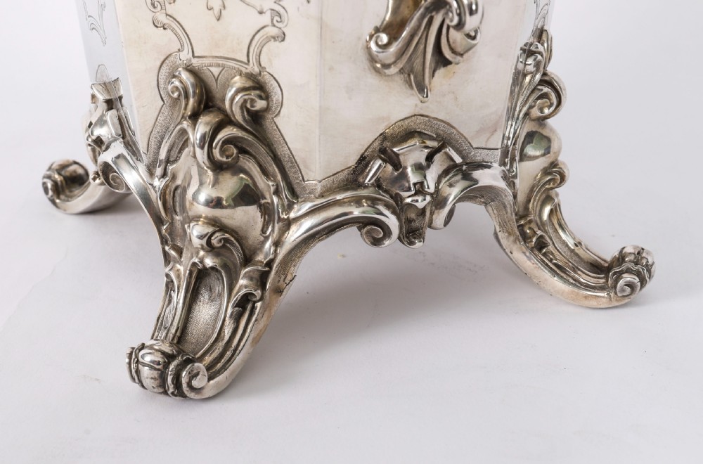 A nineteenth-century silver-plated wine cooler featuring engraved panels, cast scroll feet, side handles, and a gilded interior wash. View V