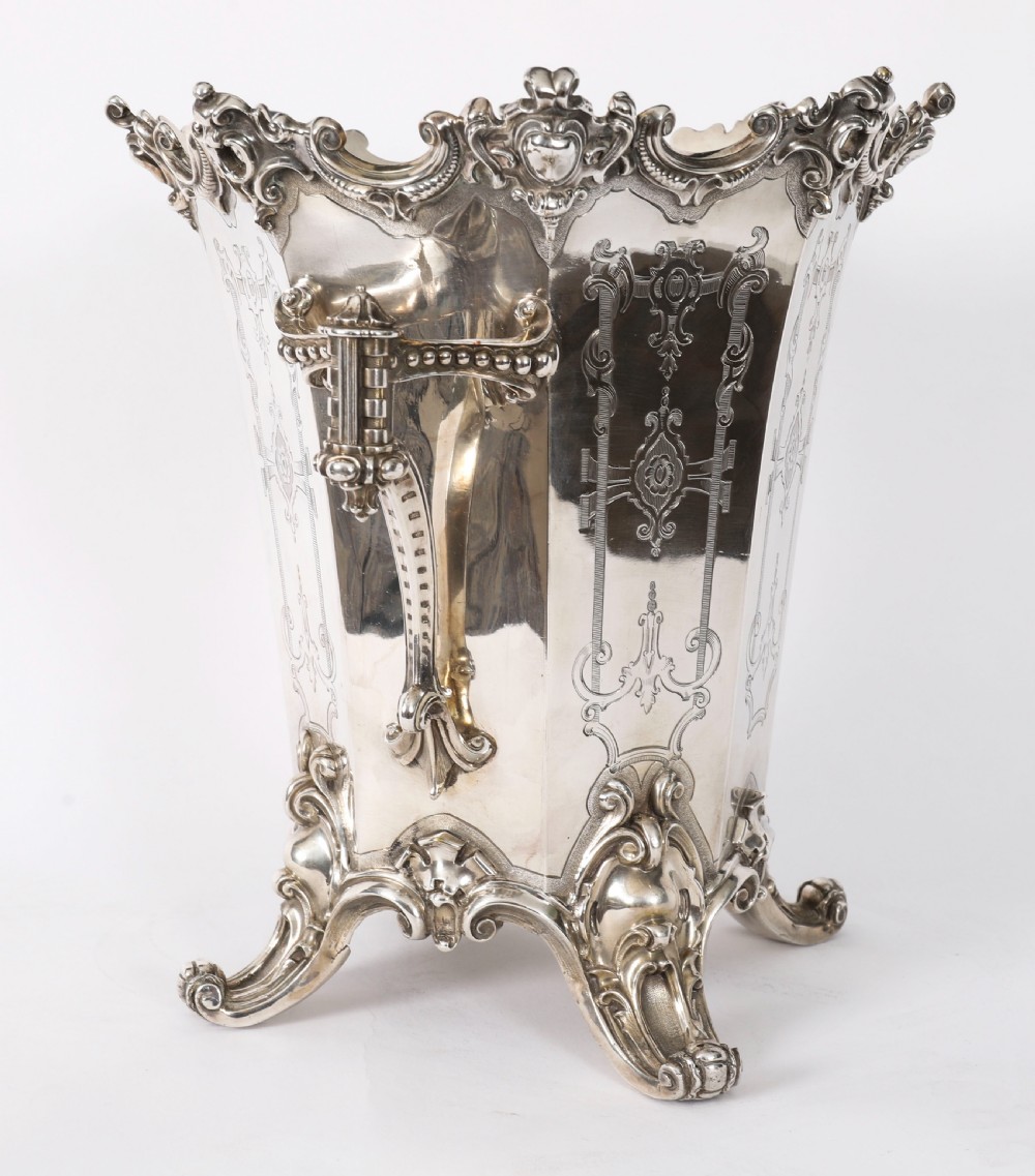 A nineteenth-century silver-plated wine cooler featuring engraved panels, cast scroll feet, side handles, and a gilded interior wash. View X