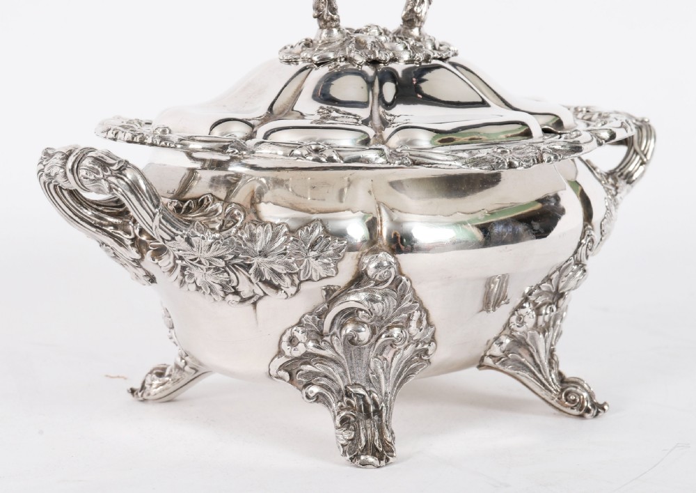 A pair of silver-plated oval sauce tureens featuring domed lids, foliate scroll handles, and decorative carved feet. View IX