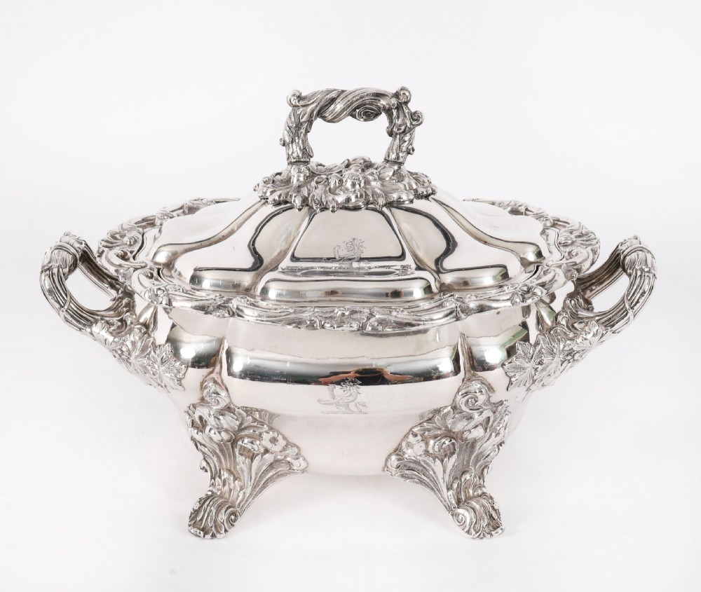 A pair of silver-plated oval sauce tureens featuring domed lids, foliate scroll handles, and decorative carved feet. View X