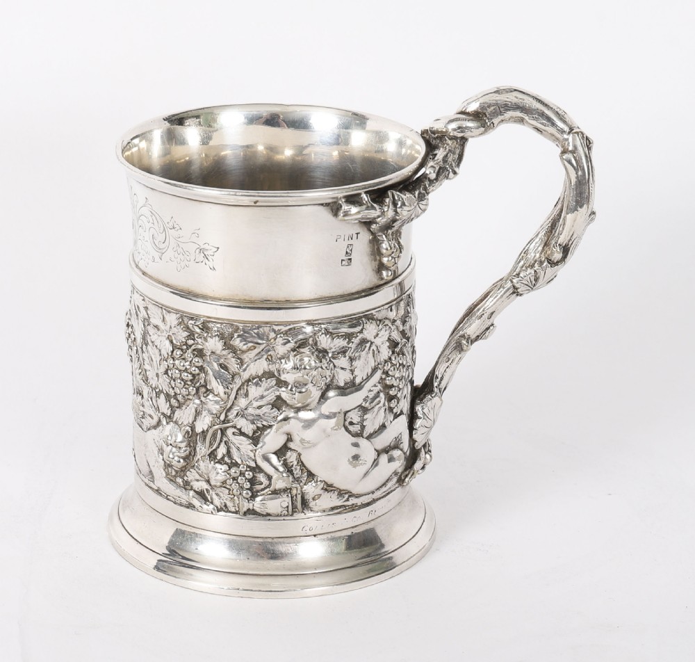 A Victorian silver-plated mug featuring embossed putti and grapevine motifs, an engraved rim, a pint capacity mark, and a naturalistic branch-shaped handle. View XI