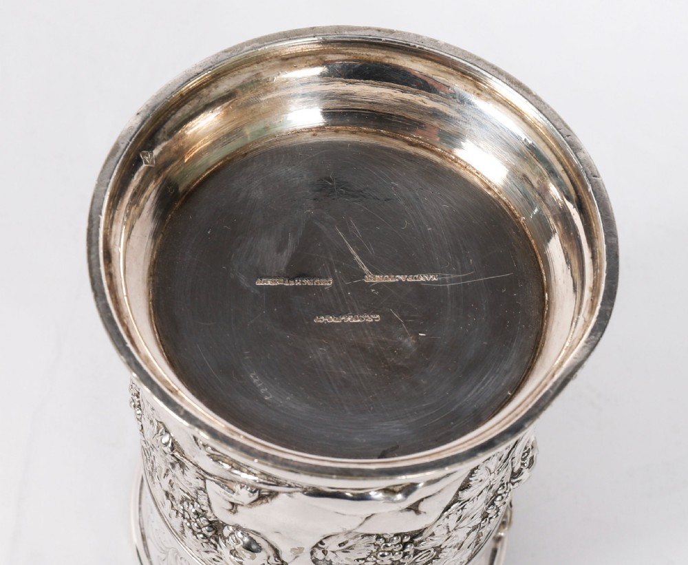 A Victorian silver-plated mug featuring embossed putti and grapevine motifs, an engraved rim, a pint capacity mark, and a naturalistic branch-shaped handle. View XIX