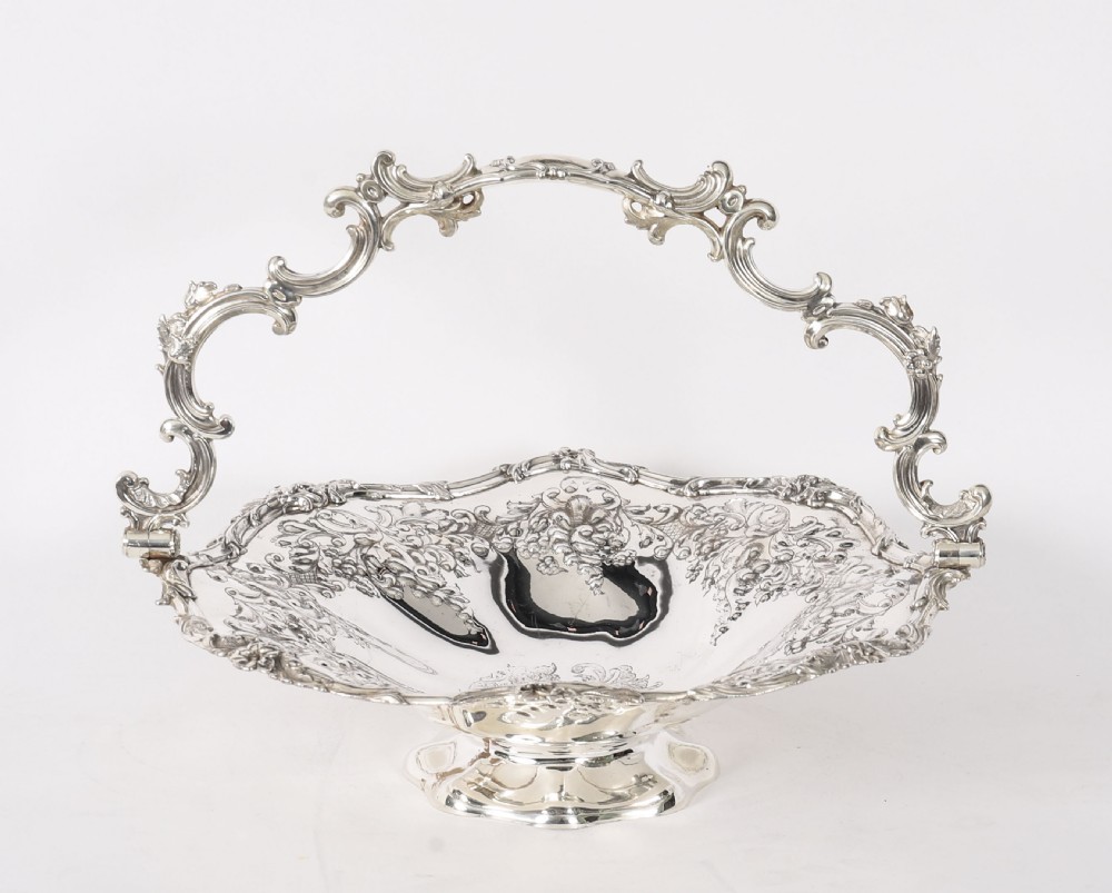 An ornate mid-19th-century Victorian silver-plated fruit basket with a high scroll swing handle, chased leaf patterns, scalloped rim, and pedestal base. View III