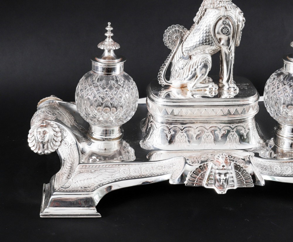 A Victorian silver-plated inkstand featuring a central winged sphinx sculpture flanked by two cut glass inkwell bottles. View VI