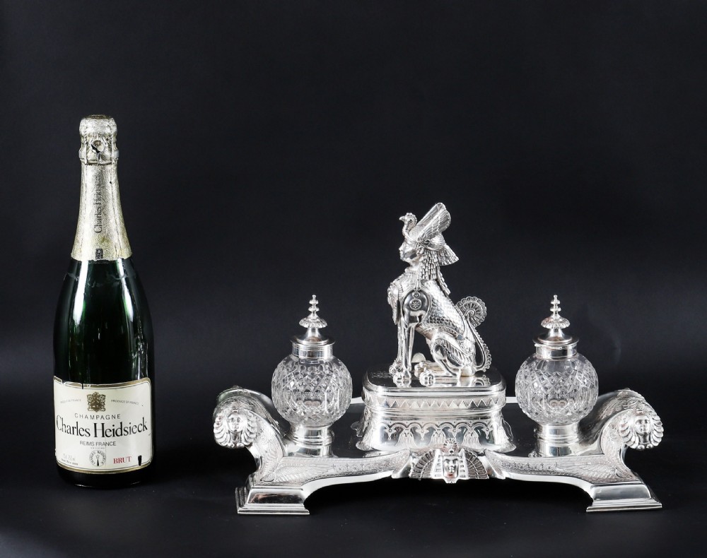 A Victorian silver-plated inkstand featuring a central winged sphinx sculpture flanked by two cut glass inkwell bottles. View XIX