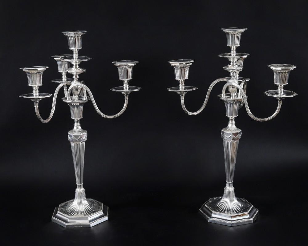 A pair of silver-plated four-light candelabra featuring fluted tapered stems, octagonal stepped bases, and curved reeded arms.