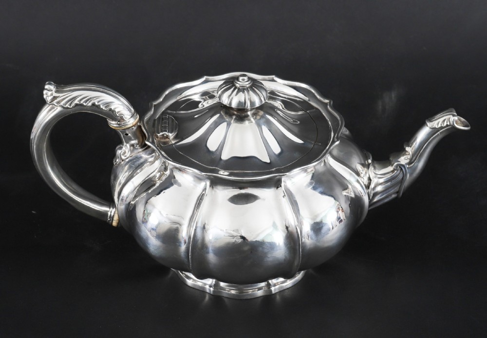 A Georgian sterling silver teapot featuring a lobed melon-shaped body, leaf-engraved spout, and insulated handle. View III