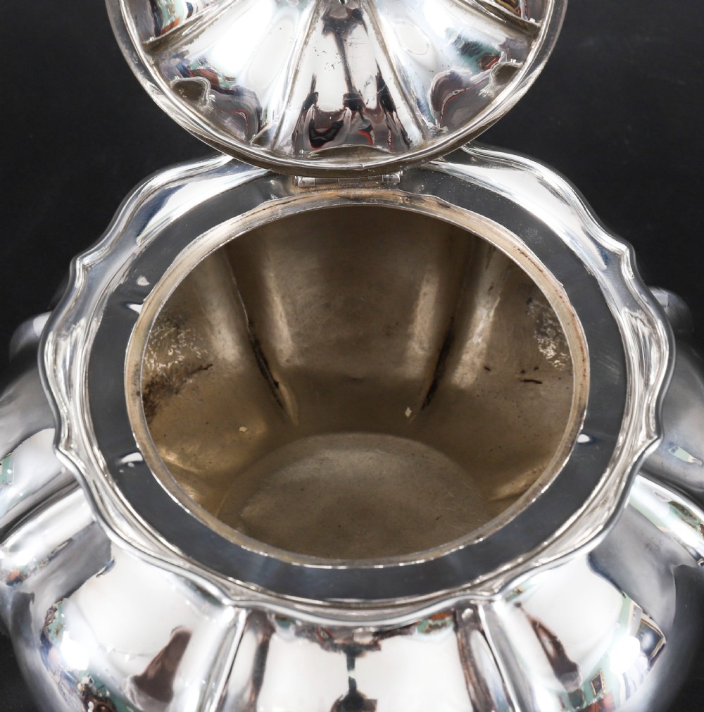 A Georgian sterling silver teapot featuring a lobed melon-shaped body, leaf-engraved spout, and insulated handle. View XII