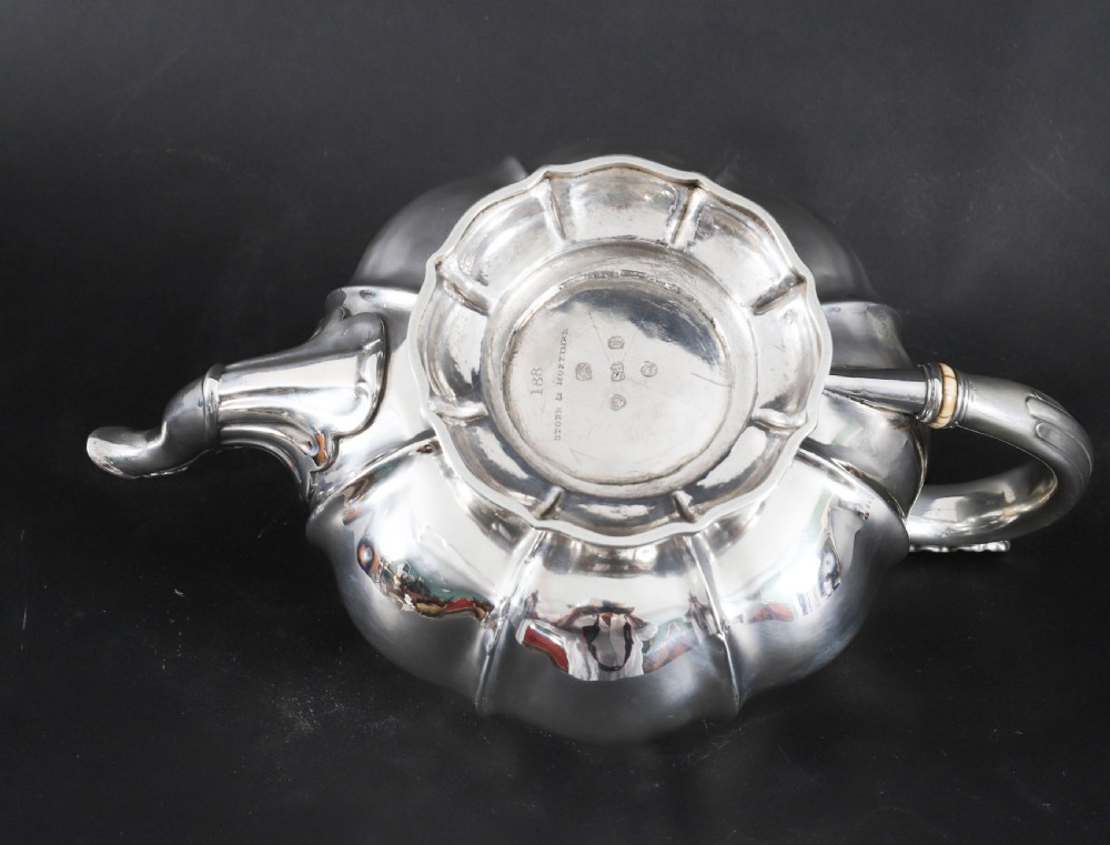 A Georgian sterling silver teapot featuring a lobed melon-shaped body, leaf-engraved spout, and insulated handle. View XIII
