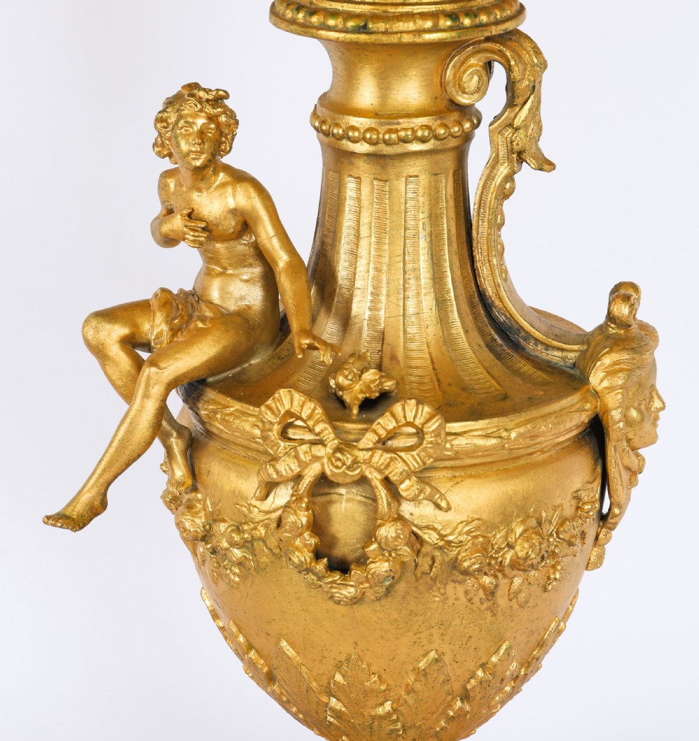 A pair of Neoclassical ormolu urn-form table lamps featuring classical figures mounted on square pink marble bases with cream pleated shades. View IV