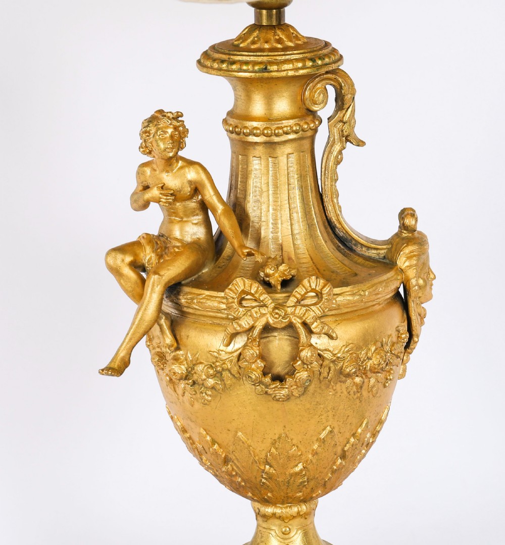 A pair of Neoclassical ormolu urn-form table lamps featuring classical figures mounted on square pink marble bases with cream pleated shades. View V