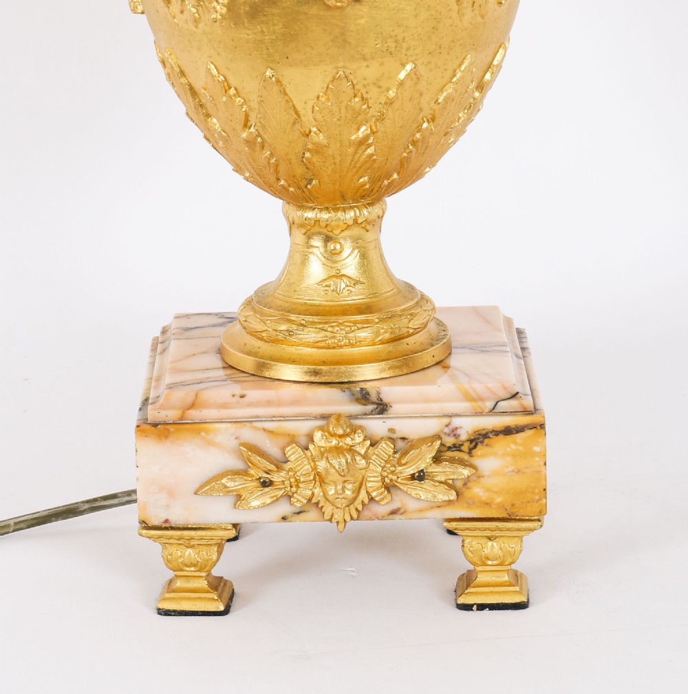 A pair of Neoclassical ormolu urn-form table lamps featuring classical figures mounted on square pink marble bases with cream pleated shades. View XIV