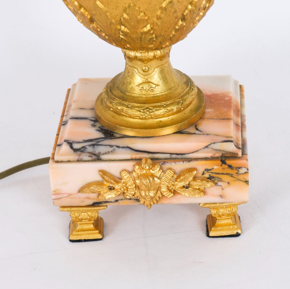 A pair of Neoclassical ormolu urn-form table lamps featuring classical figures mounted on square pink marble bases with cream pleated shades. View XVIII