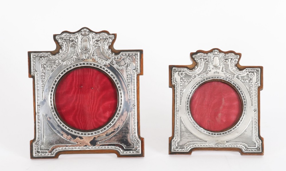A pair of Edwardian sterling silver photo frames with wooden easel backs and oval apertures lined in red fabric. View II
