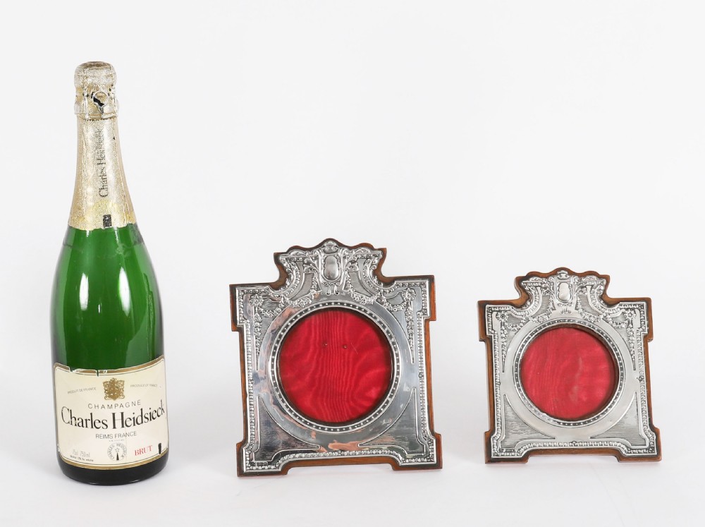 A pair of Edwardian sterling silver photo frames with wooden easel backs and oval apertures lined in red fabric. View XVII