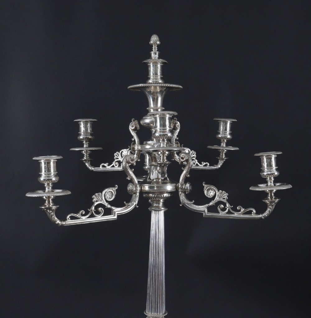 An ornate Victorian silver-plated multi-arm table centrepiece candelabra featuring scrollwork branches, a fluted column stem, and a pediment base adorned with mythical creatures. View III