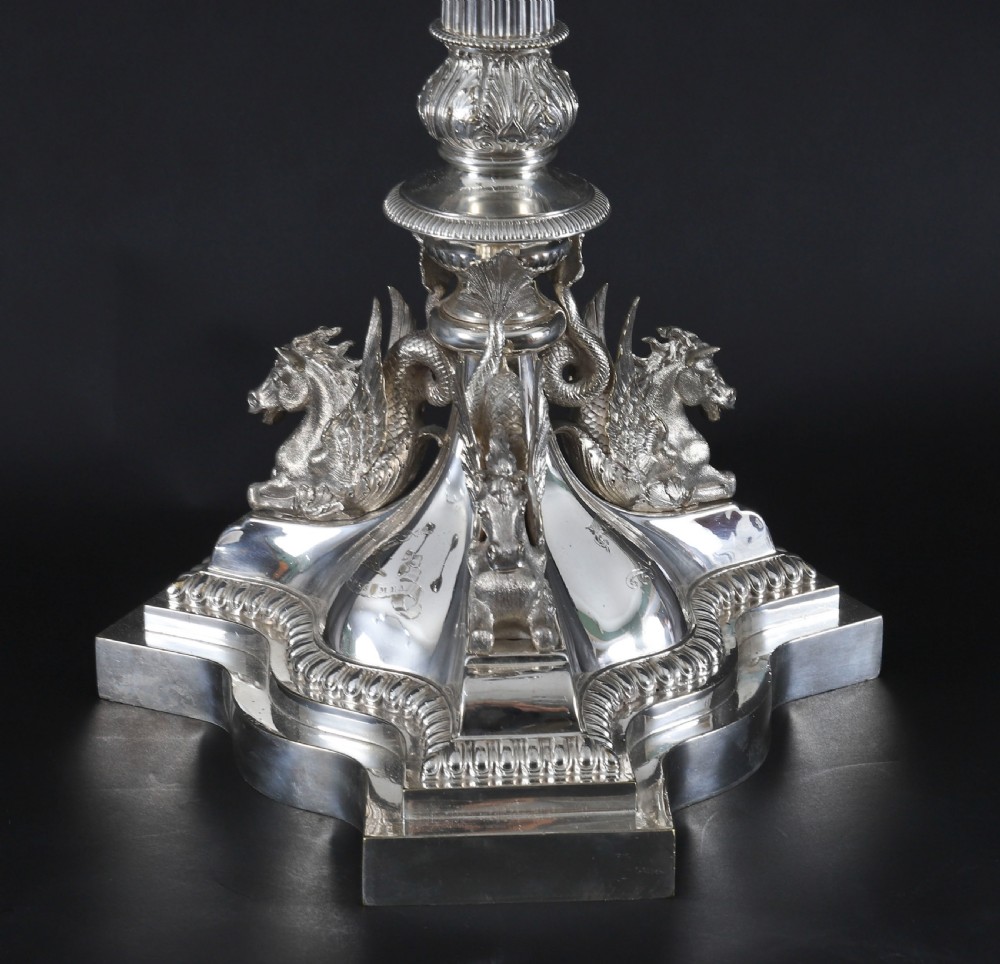 An ornate Victorian silver-plated multi-arm table centrepiece candelabra featuring scrollwork branches, a fluted column stem, and a pediment base adorned with mythical creatures. View V