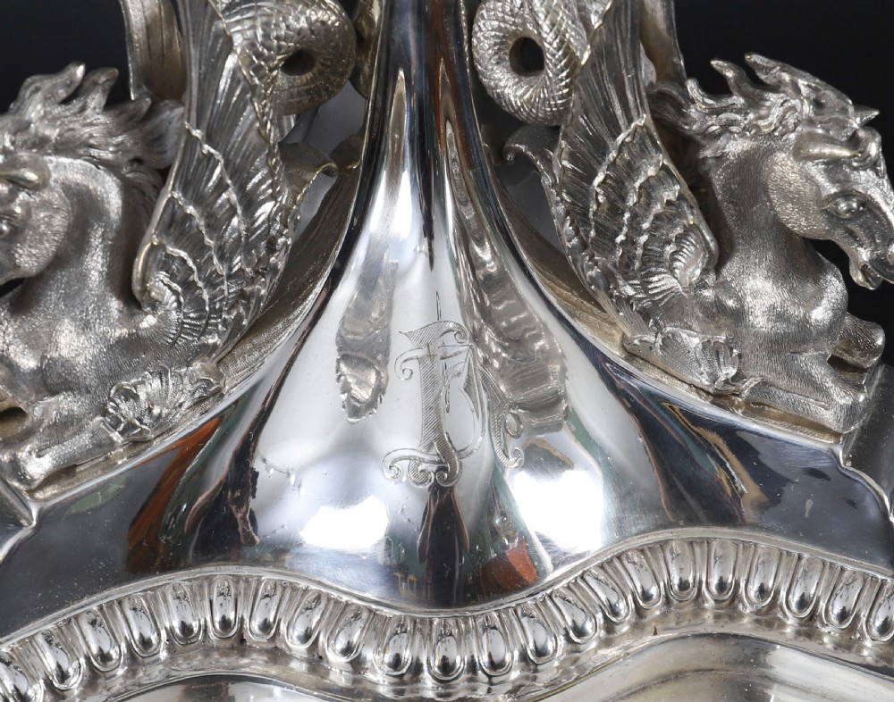 An ornate Victorian silver-plated multi-arm table centrepiece candelabra featuring scrollwork branches, a fluted column stem, and a pediment base adorned with mythical creatures. View IX