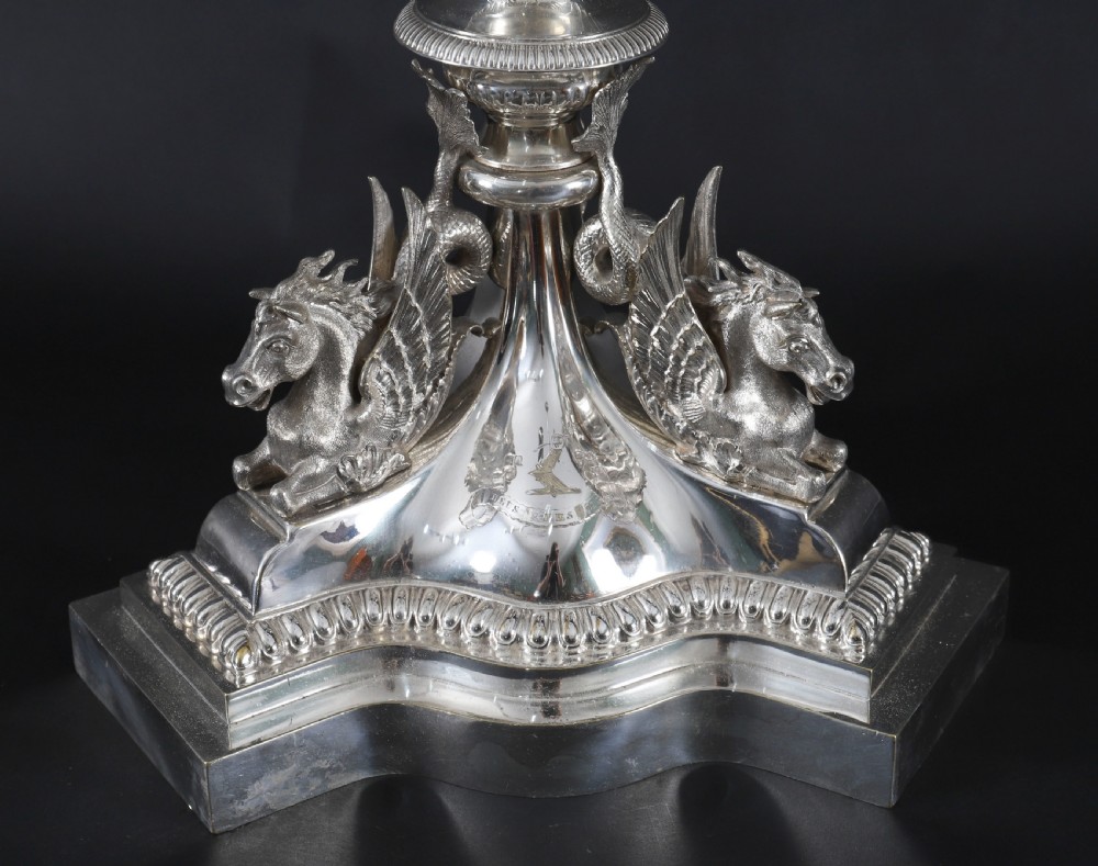 An ornate Victorian silver-plated multi-arm table centrepiece candelabra featuring scrollwork branches, a fluted column stem, and a pediment base adorned with mythical creatures. View XI