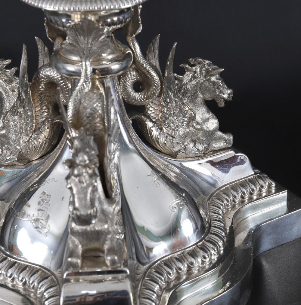 An ornate Victorian silver-plated multi-arm table centrepiece candelabra featuring scrollwork branches, a fluted column stem, and a pediment base adorned with mythical creatures. View XIV
