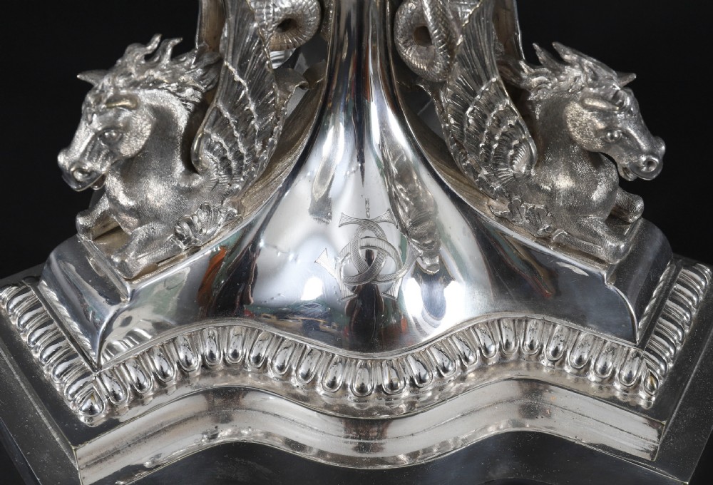 An ornate Victorian silver-plated multi-arm table centrepiece candelabra featuring scrollwork branches, a fluted column stem, and a pediment base adorned with mythical creatures. View XVI