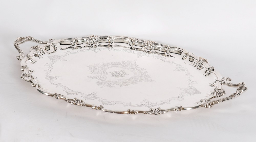 An oval Victorian silver plated serving tray featuring engraved scrollwork, cast shell borders, and dual side handles. View II