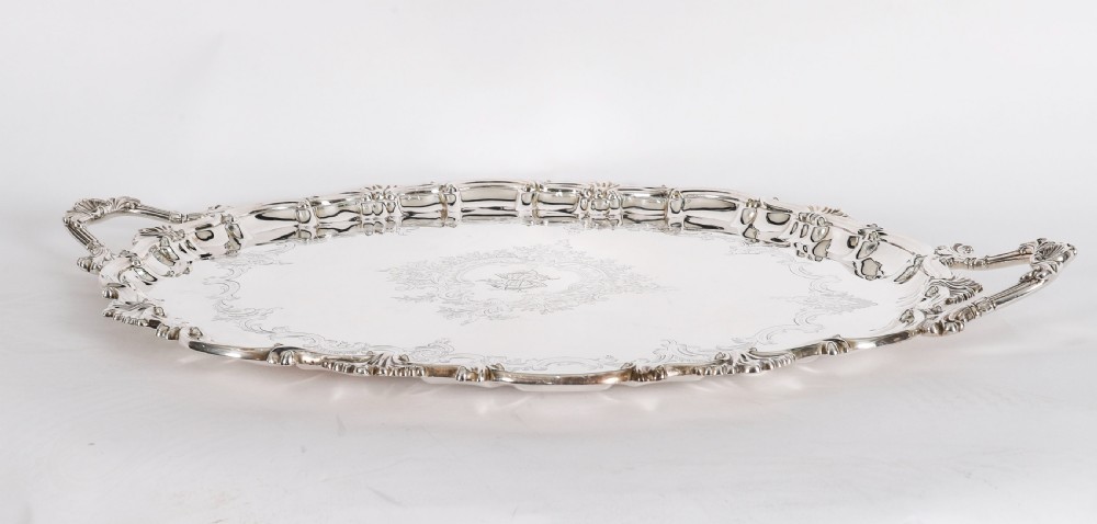 An oval Victorian silver plated serving tray featuring engraved scrollwork, cast shell borders, and dual side handles. View III