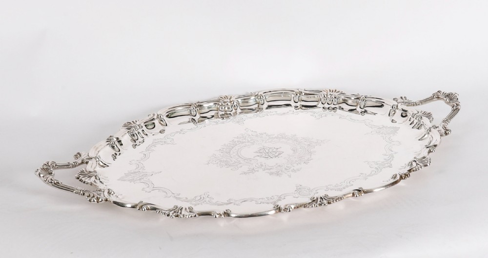 An oval Victorian silver plated serving tray featuring engraved scrollwork, cast shell borders, and dual side handles. View IV