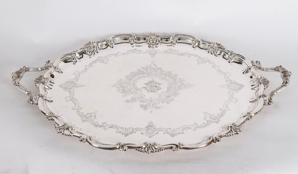 An oval Victorian silver plated serving tray featuring engraved scrollwork, cast shell borders, and dual side handles. View V