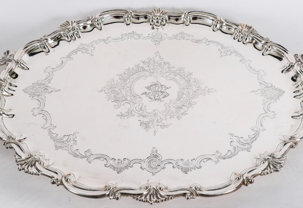 An oval Victorian silver plated serving tray featuring engraved scrollwork, cast shell borders, and dual side handles. View VI