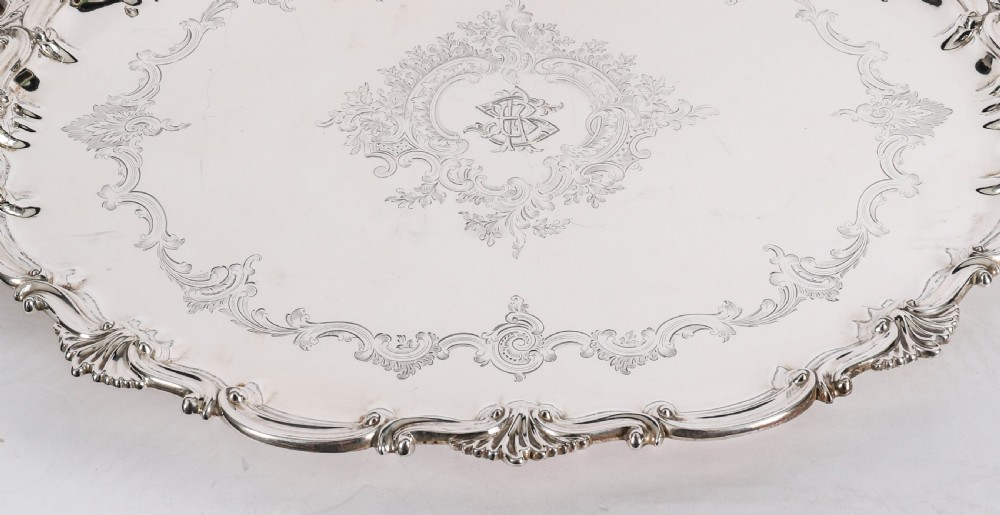 An oval Victorian silver plated serving tray featuring engraved scrollwork, cast shell borders, and dual side handles. View IX