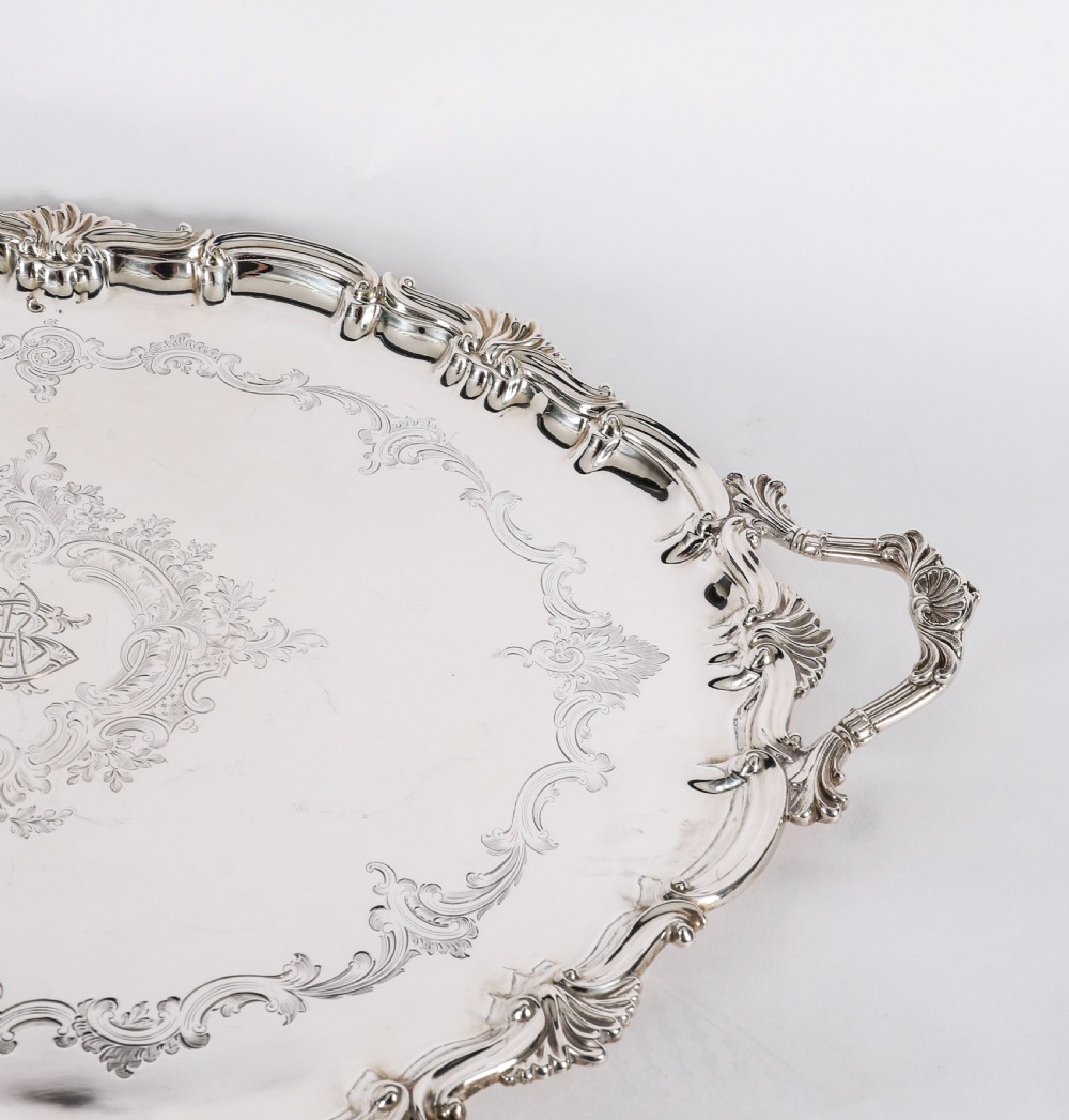 An oval Victorian silver plated serving tray featuring engraved scrollwork, cast shell borders, and dual side handles. View X