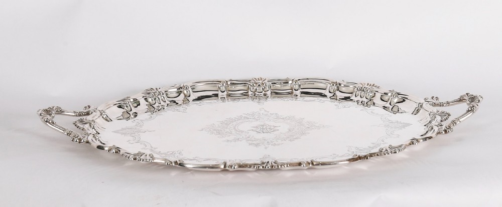 An oval Victorian silver plated serving tray featuring engraved scrollwork, cast shell borders, and dual side handles. View XIII